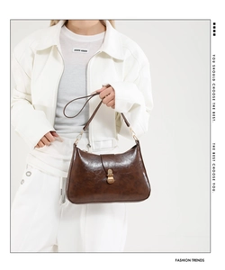 Detail of a brown vintage crescent underarm bag in glossy leather worn by a model