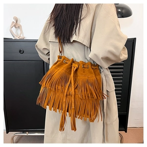 Detail of brown suede bucket bag featuring long fringe tassels and drawstring closure