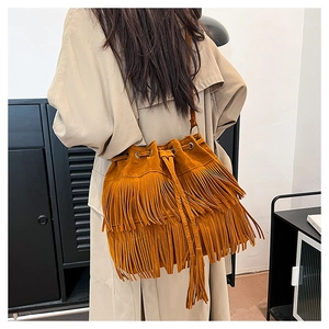 Detailed side view of a brown suede bucket bag featuring long tassels and drawstring closure