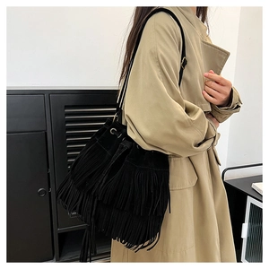 Detail of black suede bucket bag with multi-layer tassels and golden metal hardware buckles