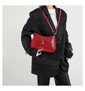 Detail of a vintage burgundy leather underarm bag featuring a metallic gold buckle