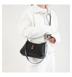 Detail of a black leather crescent shoulder bag with brown patch and gold metal clasp