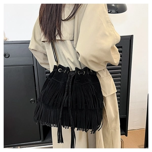 Close-up of black suede bucket bag with long tassels and vintage metal rings details
