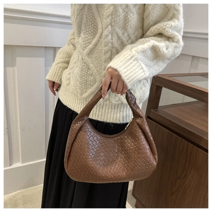 Detail of a brown woven leather hobo bag showing texture and elegant crescent shape