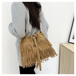Detail of tan suede bucket bag with tiered fringes and drawstring on grey wool coat
