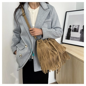 Detail of camel suede bucket bag with tiered tassels and adjustable shoulder strap