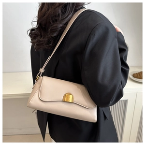 Vue détaillée du sac baguette beige en cuir avec fermoir doré porté par un mannequin