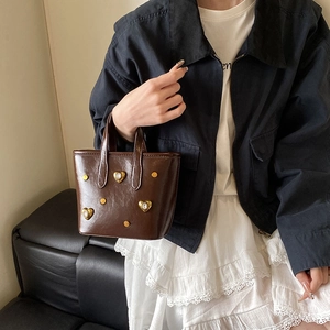 Brown leather bucket bag with crystal heart detail and rivets for a vintage trendy look