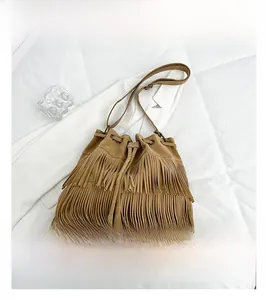 Detail of bohemian khaki suede bucket bag featuring long fringes and a drawstring closure