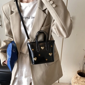 Black bucket bag with gold heart studs and sparkling crystals in casual style