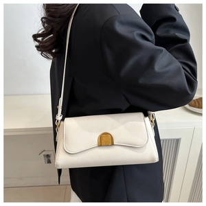 Détail d'un sac sous le bras en cuir blanc avec un fermoir en métal doré arqué