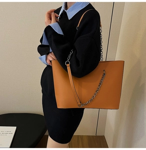 Detail of vintage brown tote bag with metal chain strap and spacious interior design