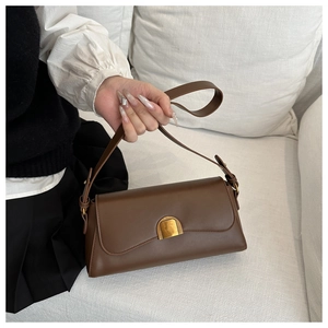Détail du sac baguette en cuir marron vintage avec boucle en métal doré et fermeture arquée