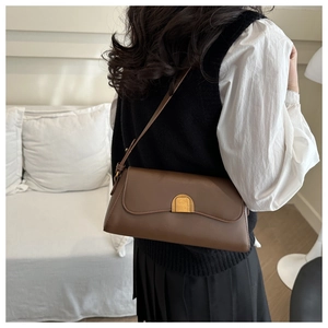 Vue détaillée d'un sac baguette en cuir marron caramel porté épaule avec boucle dorée élégante