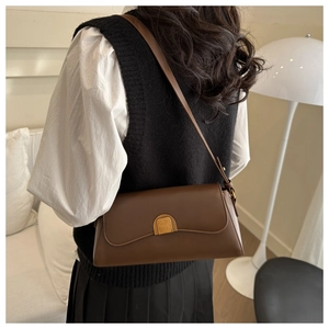 Détail du sac baguette vintage en cuir marron foncé avec fermoir doré porté par un mannequin