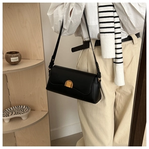 Détail d'un sac baguette en cuir noir mat avec boucle dorée et bandoulière réglable