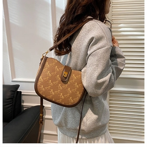 Detail of vintage brown saddle bag with horse pattern and leather strap on model