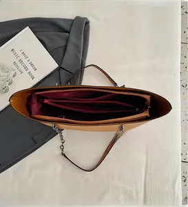 Detailed interior of khaki tote bag showing multi-layer compartments and deep red lining