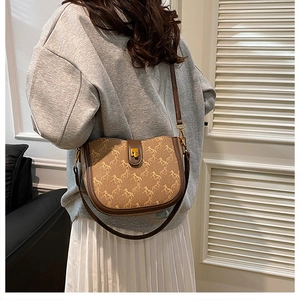 Detail of vintage saddle bag with horse print canvas and brown leather strap on model