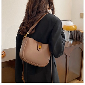 Detail of vintage brown leather saddle bag with golden square twist lock and adjustable strap