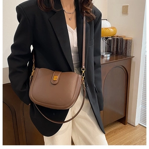 Detail of vintage brown leather saddle bag featuring a gold square buckle on a model