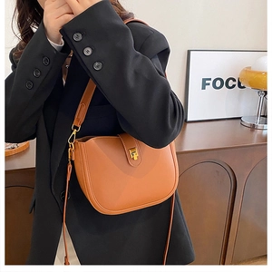 Close-up of brown leather saddle bag with gold metal buckle and adjustable strap