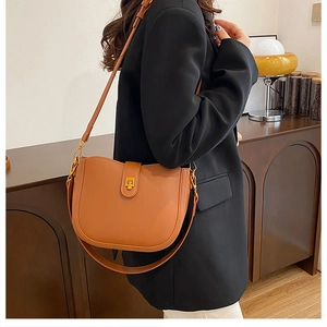 Detail of caramel leather saddle bag with vintage gold buckle on a black blazer