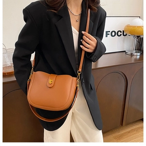Brown leather saddle bag with gold clasp styled on model with a black blazer