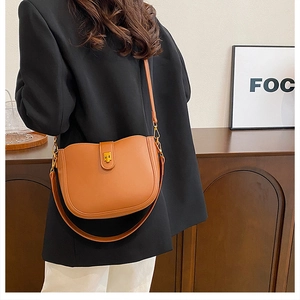 Caramel leather saddle bag with gold buckle and adjustable strap shown on model