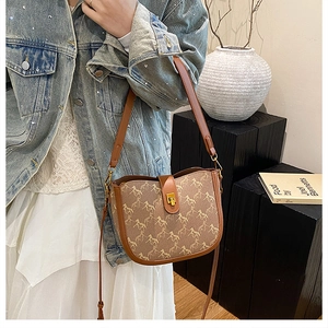 Detail of vintage saddle bag featuring classic horse print and gold metal twist lock buckle