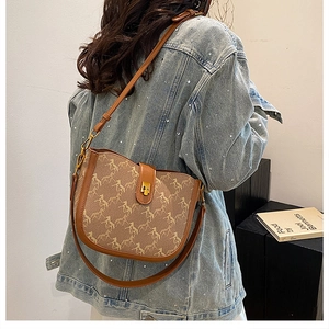 Side view of retro saddle bag with horse print pattern on model in denim jacket