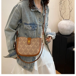Detail of vintage brown saddle bag with horse print and gold clasp on a model