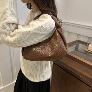 Brown woven leather hobo bag with knotted handle shown in a stylish indoor lifestyle setting