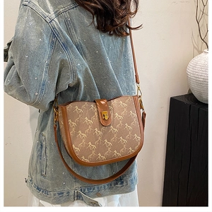 Detail of vintage saddle bag featuring horse print patterns and gold metallic buckle