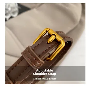 Close-up of adjustable brown leather shoulder strap with a matte gold buckle