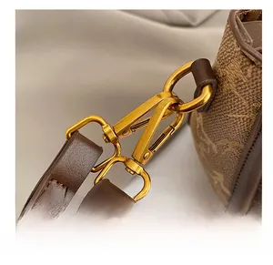 Close-up of bronze-gold lobster clasp and vintage brown leather with stitching