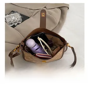 Flat lay view showing internal capacity of the brown monogram saddle bag with daily items