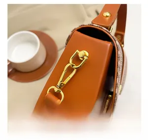 Close-up of golden metal hooks and crocodile pattern leather on the orange-brown bag