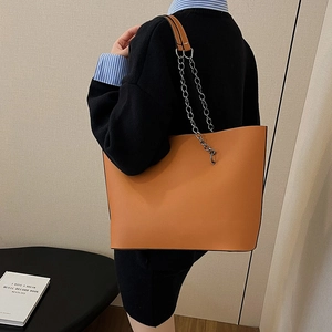 Retro orange-brown faux leather tote bag with chain strap shown on a model