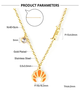 Detail of gold-plated croissant necklace with bread charm and cubic zirconia pendant