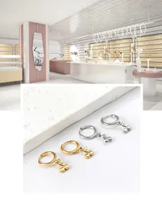 Detailed view of silver and gold cherry pendant hoop earrings on a stone base