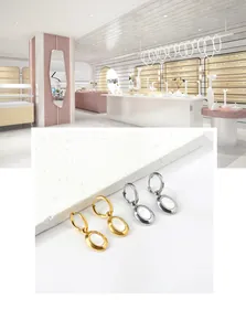 Detail of 18k gold and silver oval drop earrings featuring white mother of pearl inlay