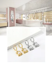 Dettaglio di orecchini a cerchio classici in oro e argento con pendenti di perle quadrate