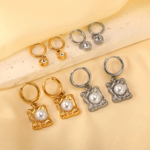 Set di orecchini a cerchio in oro e argento con perle e cristalli su vassoio in pietra