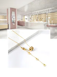 Vue détaillée d'un collier pendentif cylindre doré avec zircon et disques gravés sur la chaîne