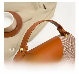 Close-up of brown leather handle and woven texture bag with golden metal rivets