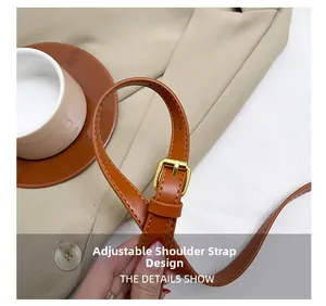 Detail of adjustable brown leather shoulder strap with a polished gold metal buckle