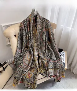 Détail d'un châle en soie paisley élégant aux motifs baroques sur un canapé beige