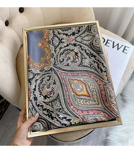 Détail d'un foulard en soie à motif paisley avec cadre doré sur fond chaleureux