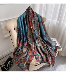 Détail d'une écharpe en soie à motif paisley bleu canard drapée sur une chaise